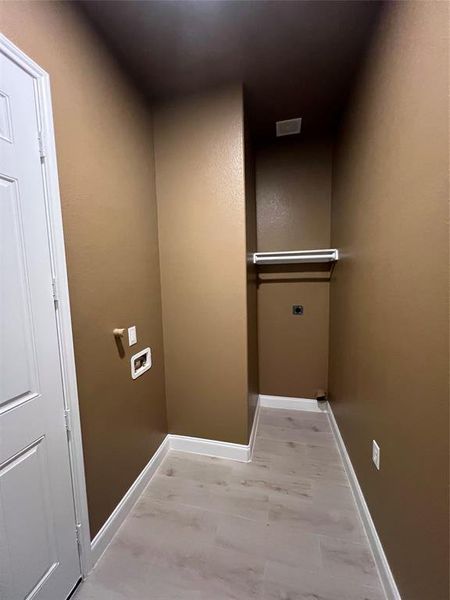 Laundry area with light hardwood / wood-style floors and hookup for an electric dryer