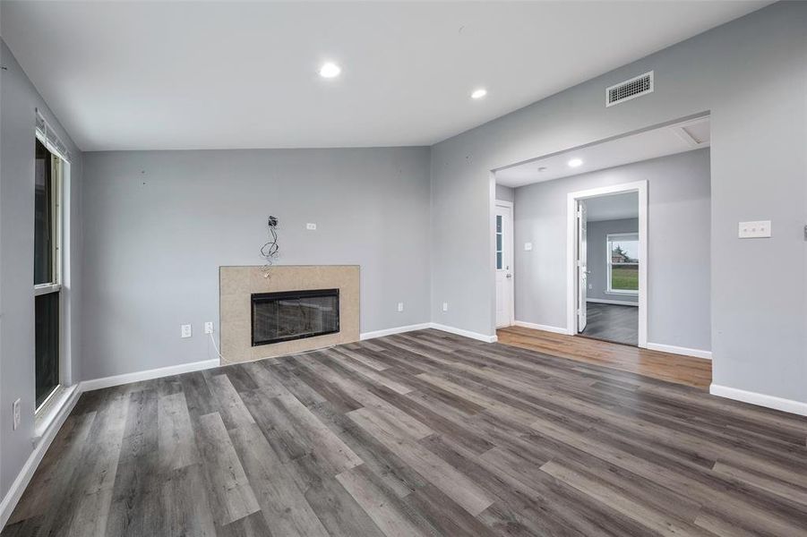 Unfurnished living room with dark wood-type flooring, lofted ceiling, and a fireplace