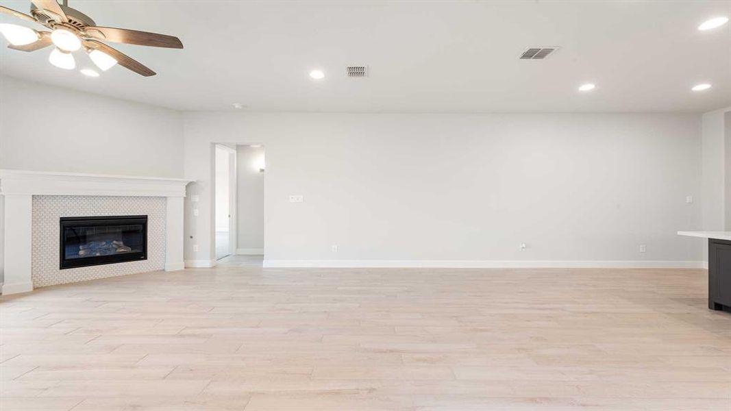 Unfurnished living room featuring light wood-type flooring, a fireplace, and ceiling fan