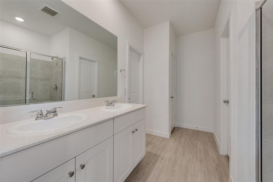 Bathroom featuring a shower with shower door, double sink vanity, and hardwood / wood-style floors