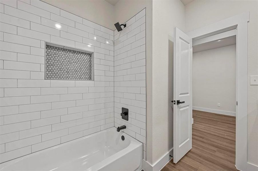 Bathroom with tiled shower / bath combo and hardwood / wood-style floors