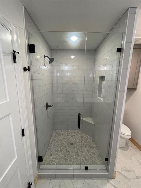 Bathroom with tile patterned flooring, walk in shower, and toilet