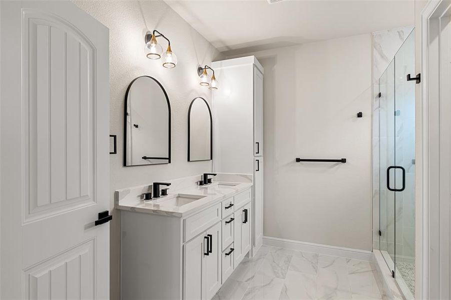 Bathroom with tile patterned floors, double sink vanity, and an enclosed shower