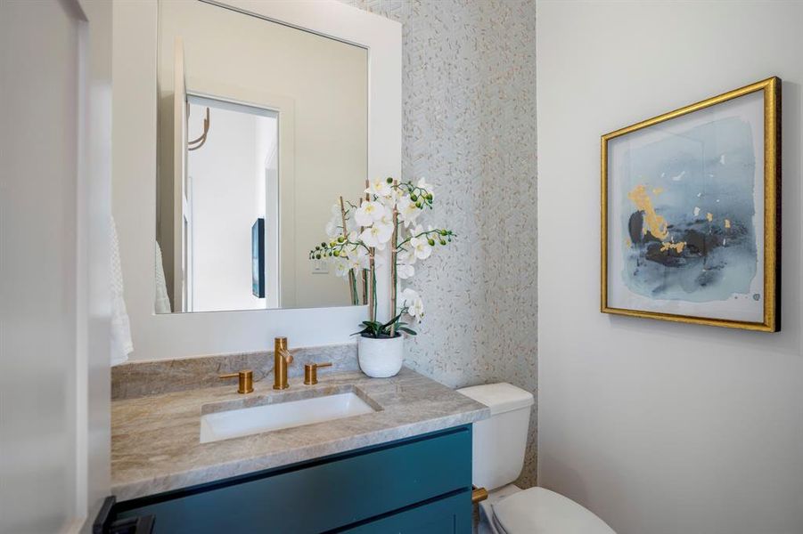 Incredible selections of counters and hardware grace this powder bath with an accent wall.
