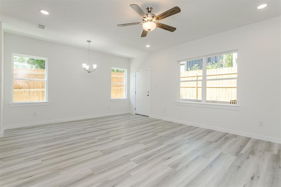 Spare room with light hardwood / wood-style flooring and ceiling fan with notable chandelier