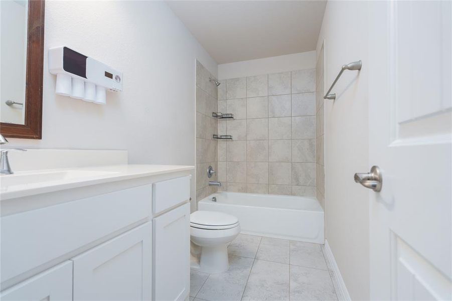 Full bathroom with vanity, tile patterned flooring, tiled shower / bath, and toilet