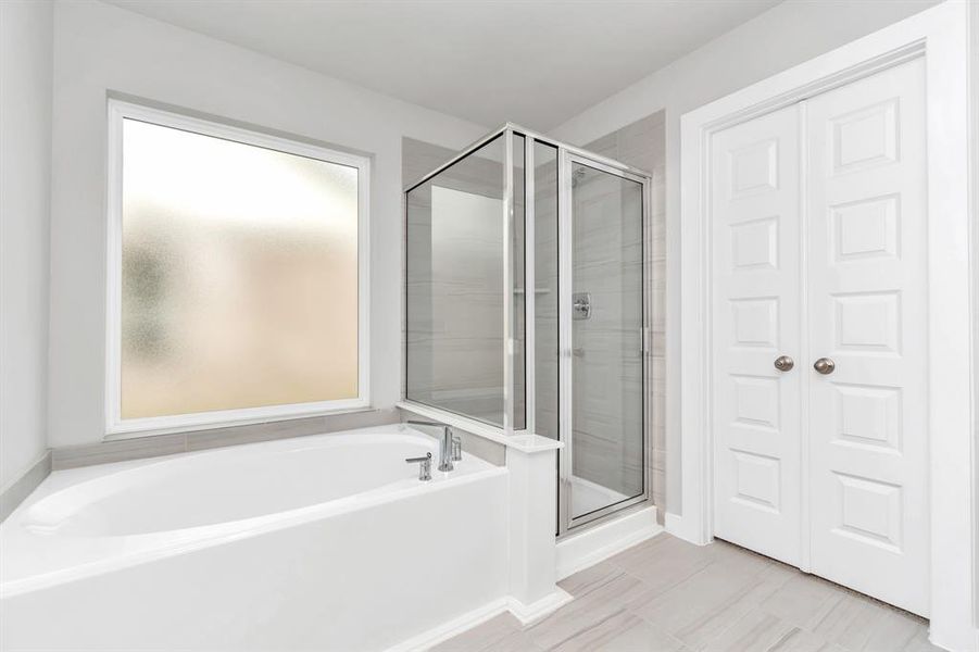 The primary en-suite has a soaking tub to give you that spa experience. The large privacy window allow lots of nature light in the space. Sample photo of completed home with similar floor plan. As-built interior colors and selections may vary.