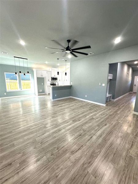 Unfurnished living room with light hardwood / wood-style floors and ceiling fan