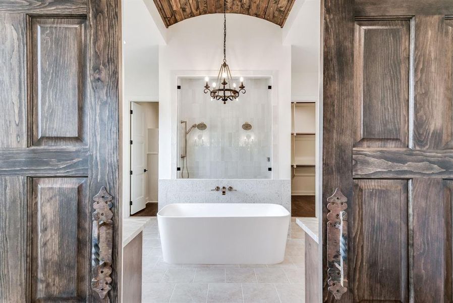 Bathroom featuring a notable chandelier, shower with separate bathtub, lofted ceiling, and tile patterned flooring