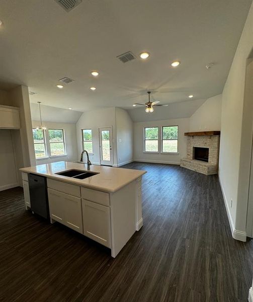 Kitchen with sink, vaulted ceiling, white cabinetry, a healthy amount of sunlight, and dishwashing machine