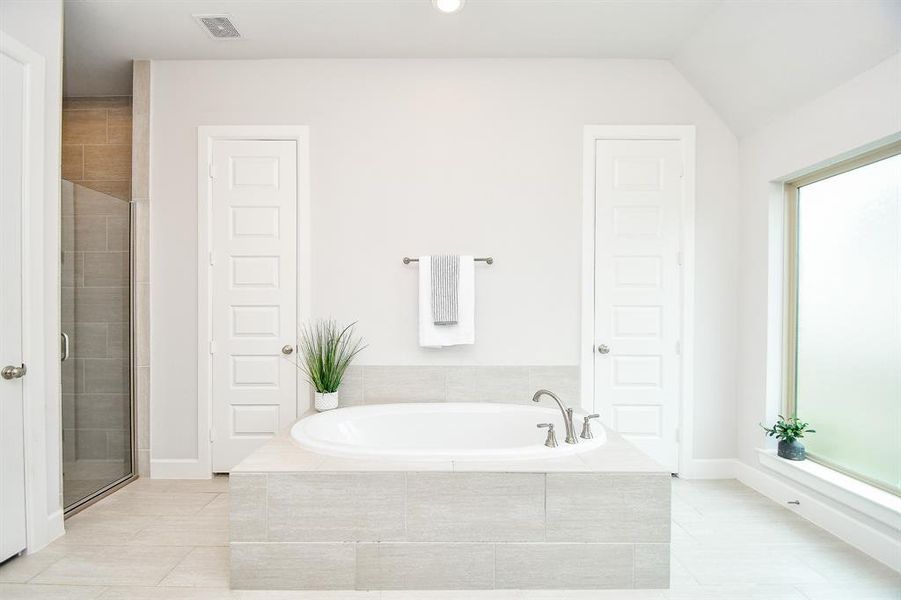 The primary modern, bright bathroom features a large built-in bathtub with tile surround, a separate walk-in shower with glass doors, 2 walk-in closets, 2 separate vanities and separate toilet room