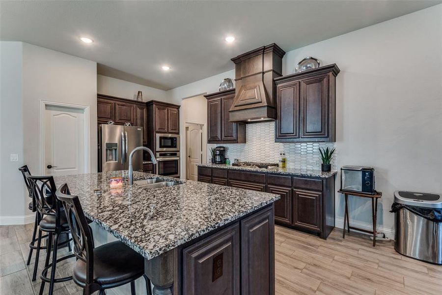 Kitchen featuring a kitchen island with sink, appliances with stainless steel finishes, sink, and light hardwood / wood-style flooring