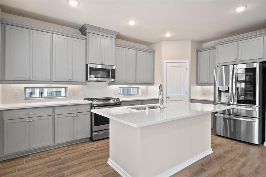 This stunning kitchen displays such a beautiful contrast with the grey cabinets, custom neutral paint, granite countertops, white modern backsplash, and SS appliances, oversized kitchen island with extra storage, breakfast bar, recessed lighting and pantry.