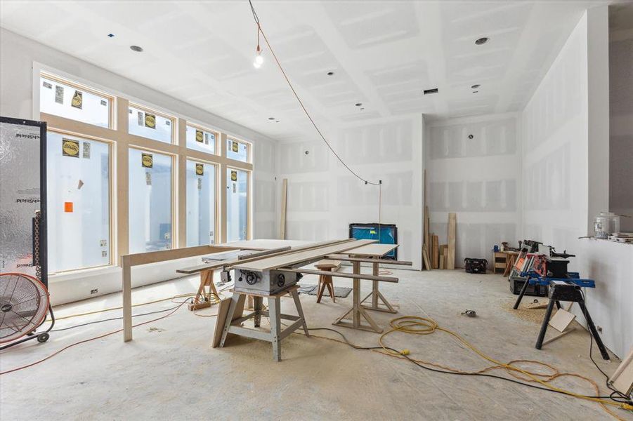 The living room is open to the kitchen area and flooded with warm natural light from the backyard. The gas log fireplace will be flanked with custom cabinetry and complete with a cast stone surround.  A stunning wet bar area will be located at the right of this picture.  Photo as of 9/3/2024