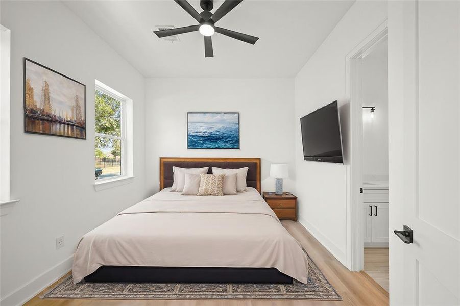 Virtually Staged: Beautiful secondary bedroom with luxury vinyl plank floors, a ceiling fan, and a complete en-suite bathroom. It is located on the first floor and can be a great guest suite. Photos are from a similar unit in the development.