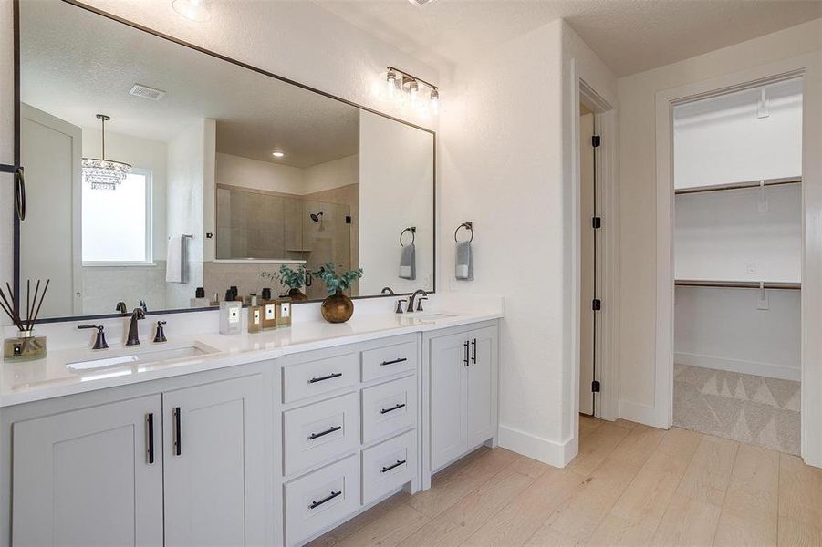 Bathroom with wood-type flooring, double sink vanity, a chandelier, and an enclosed shower