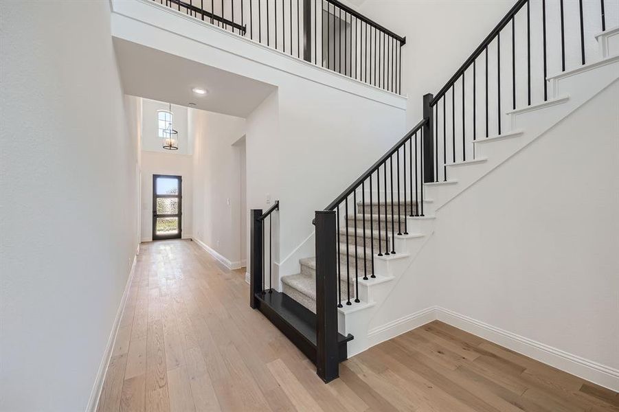 Stairs featuring wood-type flooring, a chandelier, and a high ceiling