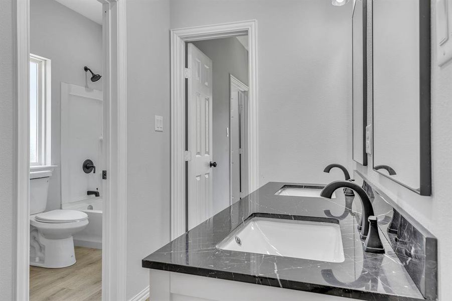 Full bathroom featuring vanity, wood-type flooring, washtub / shower combination, and toilet