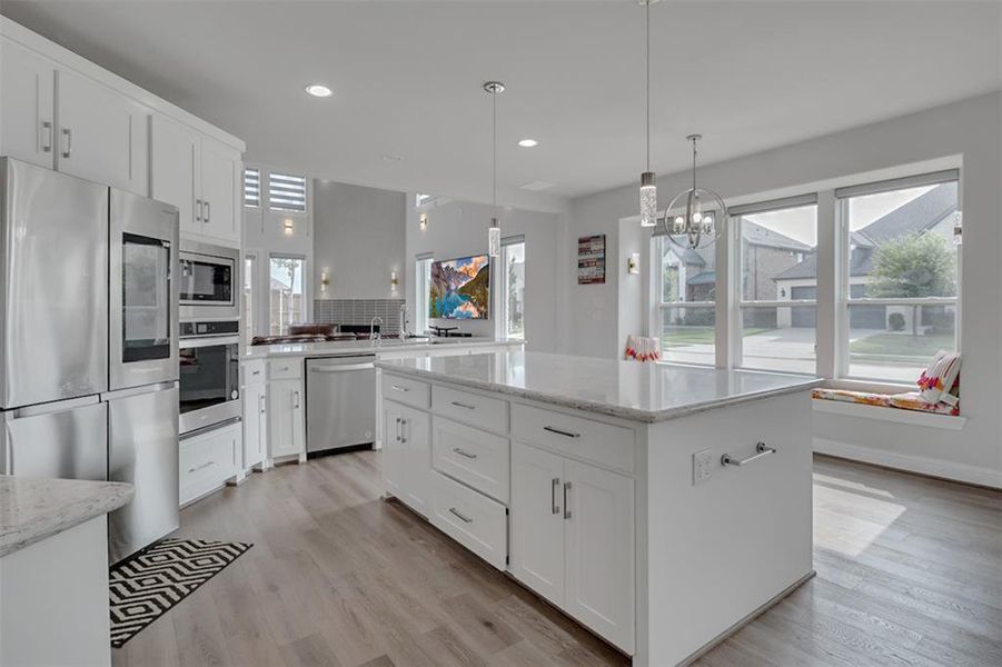 Kitchen with a kitchen island, light hardwood / wood-style flooring, tasteful backsplash, and appliances with stainless steel finishes