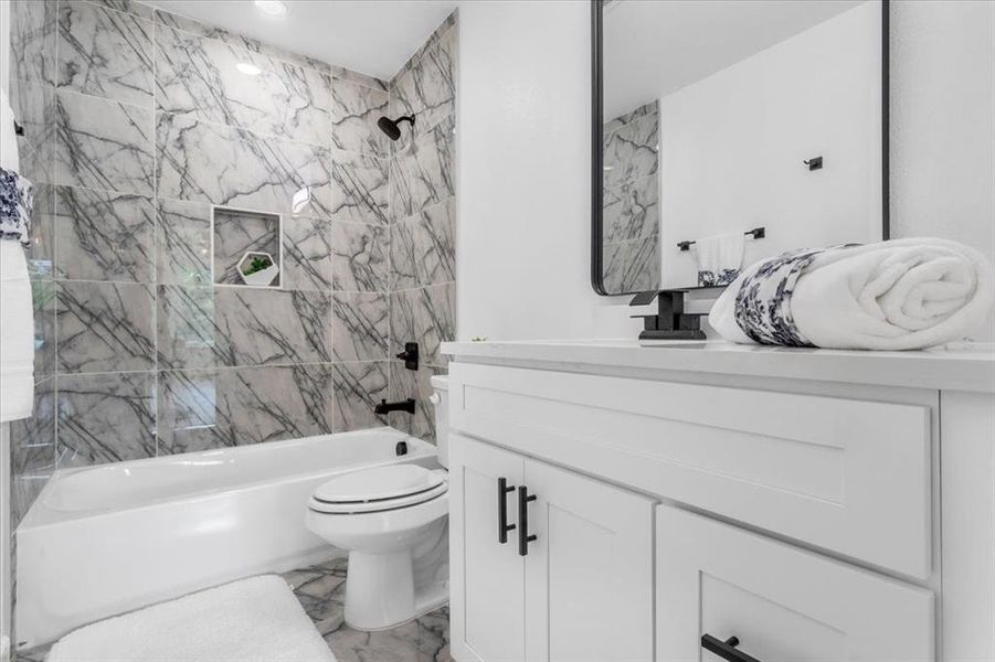 Full bathroom featuring toilet, tile floors, tiled shower / bath combo, and oversized vanity