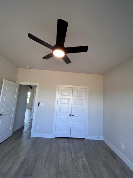 Unfurnished bedroom featuring a closet, ceiling fan, and dark wood-type flooring