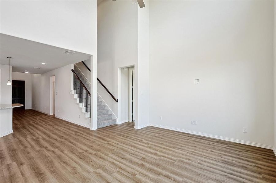 Unfurnished living room with a high ceiling, light wood-type flooring, and ceiling fan