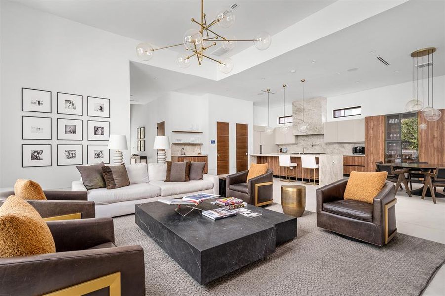 This open-concept space is an architectural masterpiece. The stunning kitchen is highlighted by a large island with a waterfall Taj Mahal quartzite countertop, modern pendant lighting, and custom Madeval cabinetry that provides ample storage.