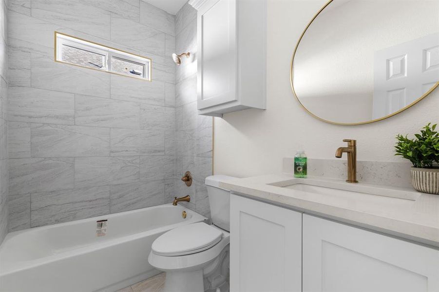 Full bathroom featuring tiled shower / bath, vanity, and toilet