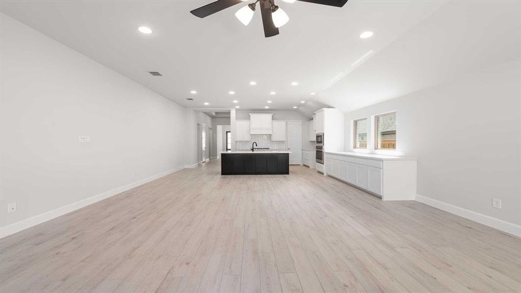 Unfurnished living room with lofted ceiling, light hardwood / wood-style floors, sink, and ceiling fan