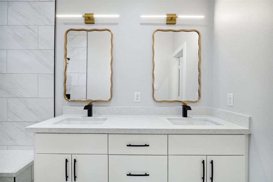 Double vanity in primary bath. Quartz countertops, black fixtures and hardware, and unique mirrors and light fixtures!