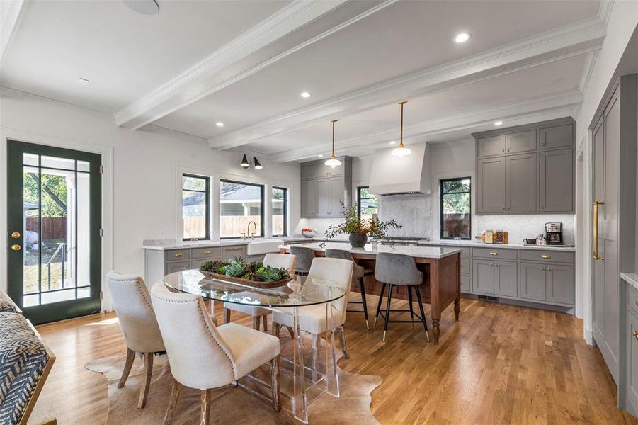 Dining room featuring light hardwood / wood-style floors, a healthy amount of sunlight, ornamental molding, and beam ceiling