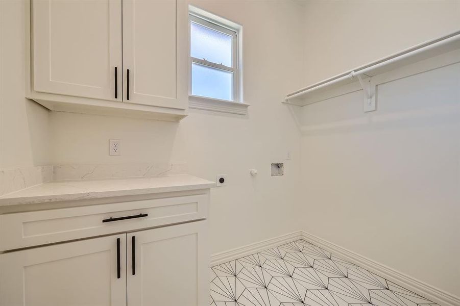 Laundry room featuring hookup for a washing machine, hookup for an electric dryer, light tile patterned floors, and cabinets