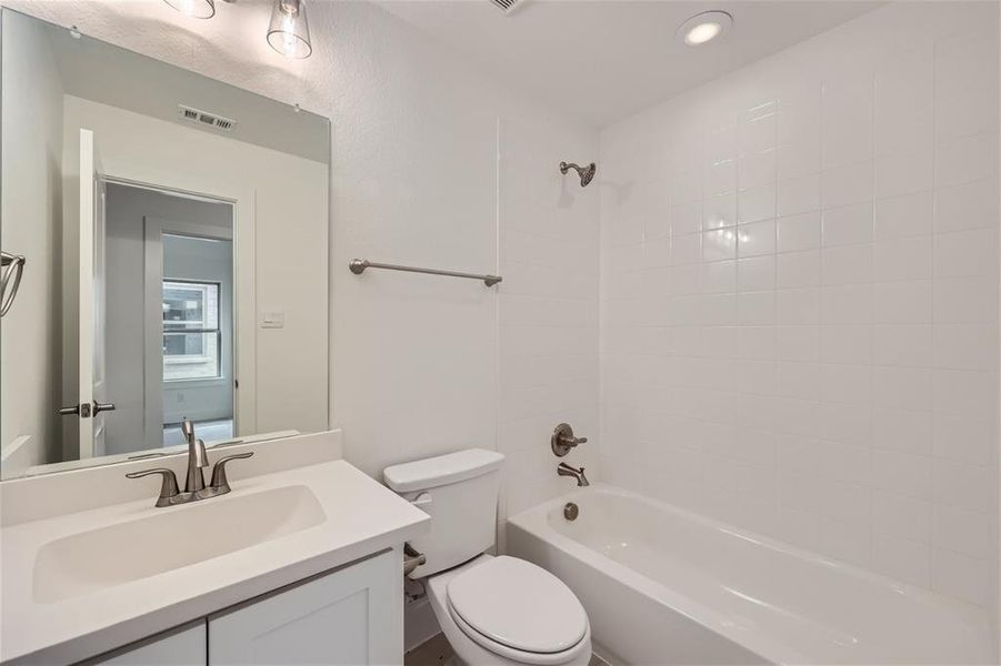 Full bathroom featuring tiled shower / bath, vanity, and toilet