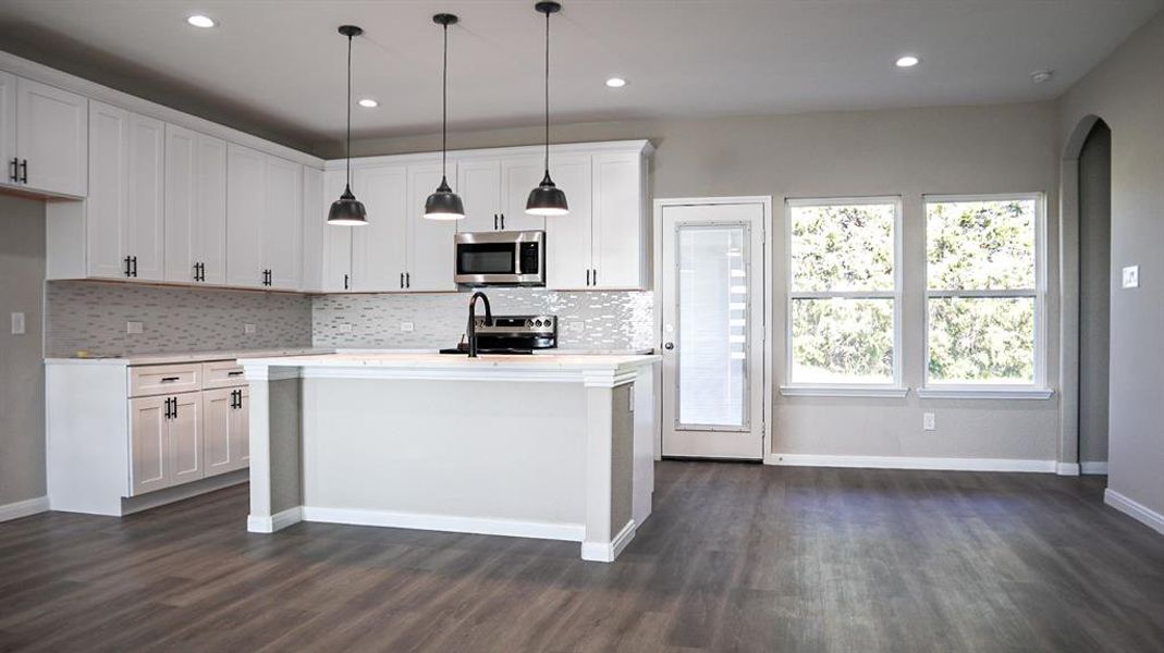 Kitchen featuring dark wood-type flooring, appliances with stainless steel finishes, and white cabinets