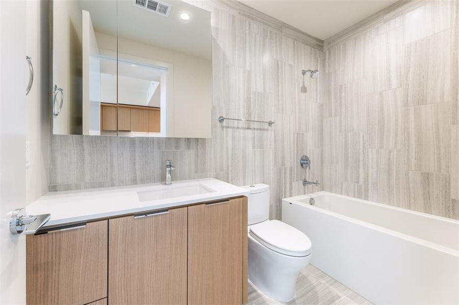 The guest bathroom has luxury finishes and a shower/tub combination