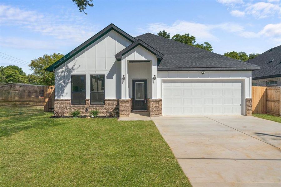 Modern farmhouse style home featuring a garage and a front lawn