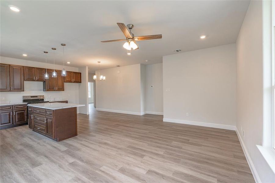 Kitchen with a center island, ceiling fan with notable chandelier, hanging light fixtures, and light hardwood / wood-style floors