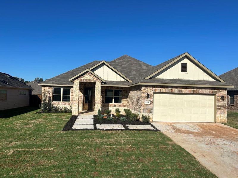 View of front of home featuring a garage, covered porch, and a front yard