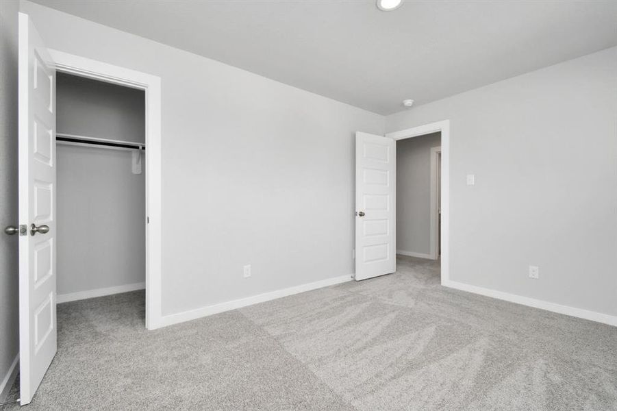 Secondary bedroom. Plush carpet, neutral paint color, large windows, and spacious closets.