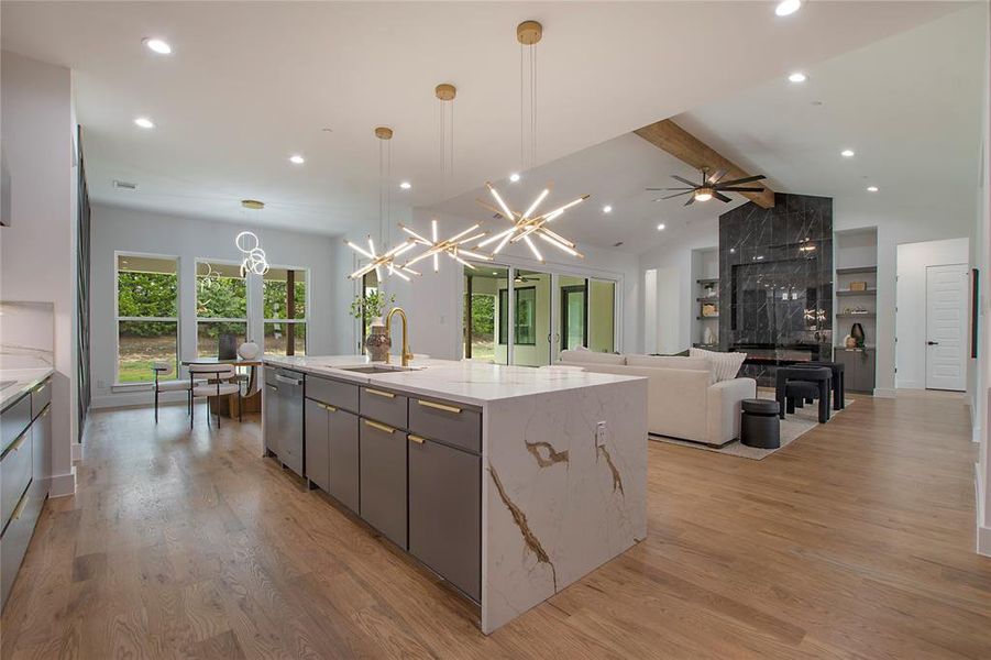 Kitchen featuring sink, pendant lighting, a center island with sink, and light hardwood / wood-style floors