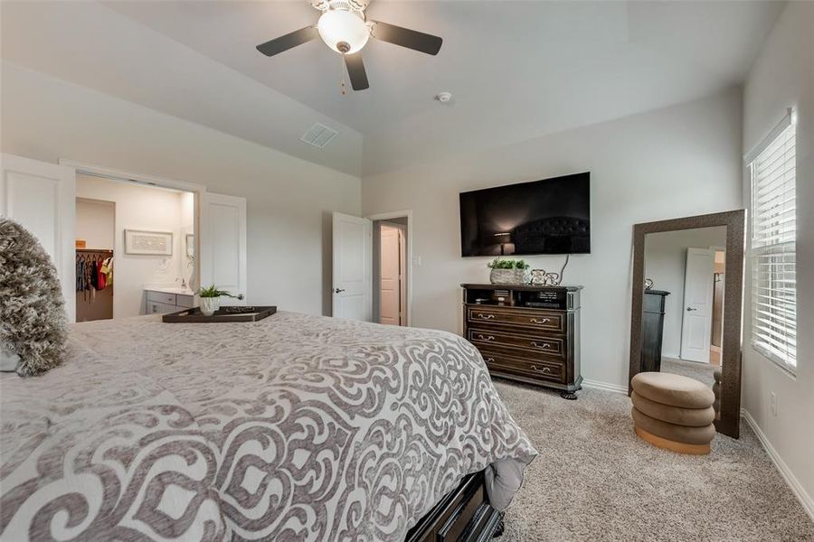 Bedroom with a closet, ceiling fan, light colored carpet, ensuite bath, and a spacious closet