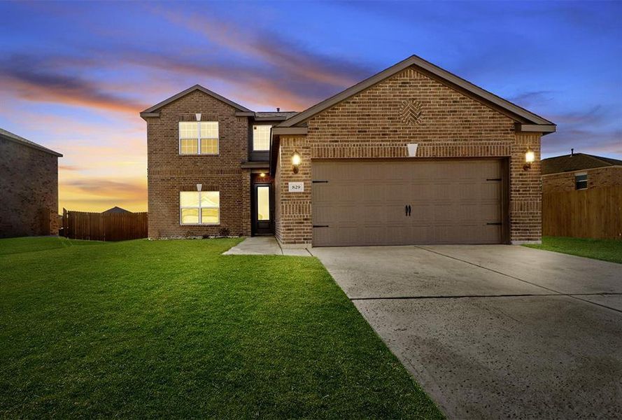 View of front property featuring a lawn and a garage