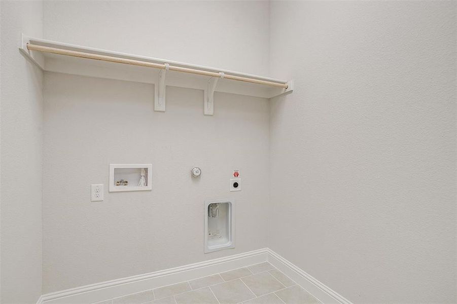 Clothes washing area featuring hookup for an electric dryer, hookup for a gas dryer, hookup for a washing machine, and tile patterned floors