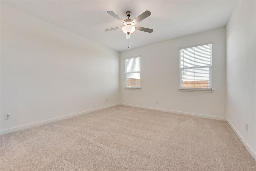 Carpeted empty room featuring ceiling fan