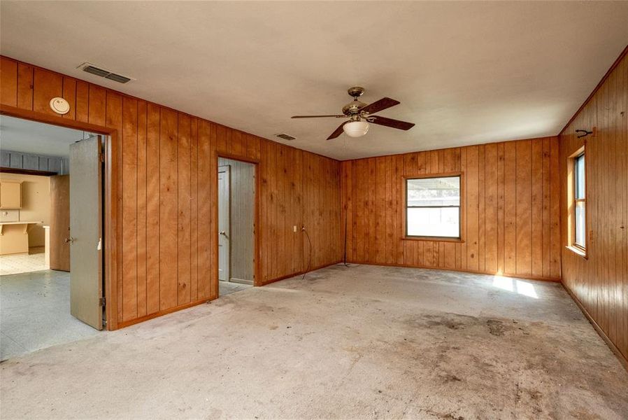 Empty room featuring ceiling fan and wooden walls