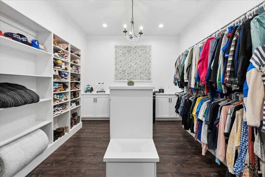 Walk in closet featuring dark hardwood / wood-style flooring and an inviting chandelier