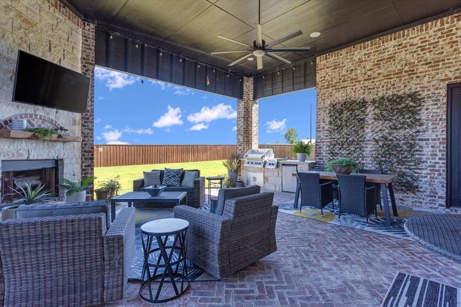 View of patio with a grill, an outdoor living space with a fireplace, ceiling fan, and exterior kitchen