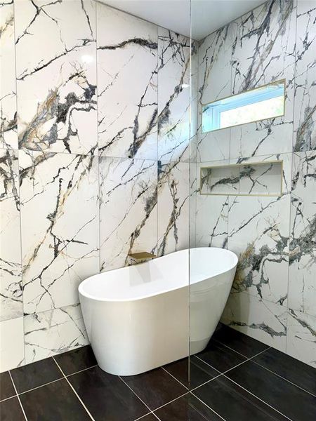 Bathroom with tile walls, tile patterned floors, and a bathtub