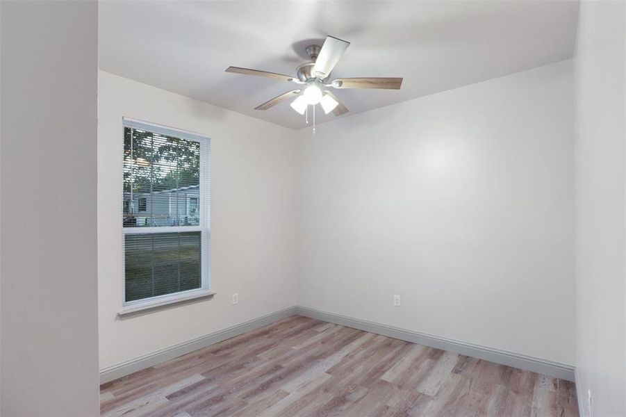 Empty room with ceiling fan and light wood-type flooring