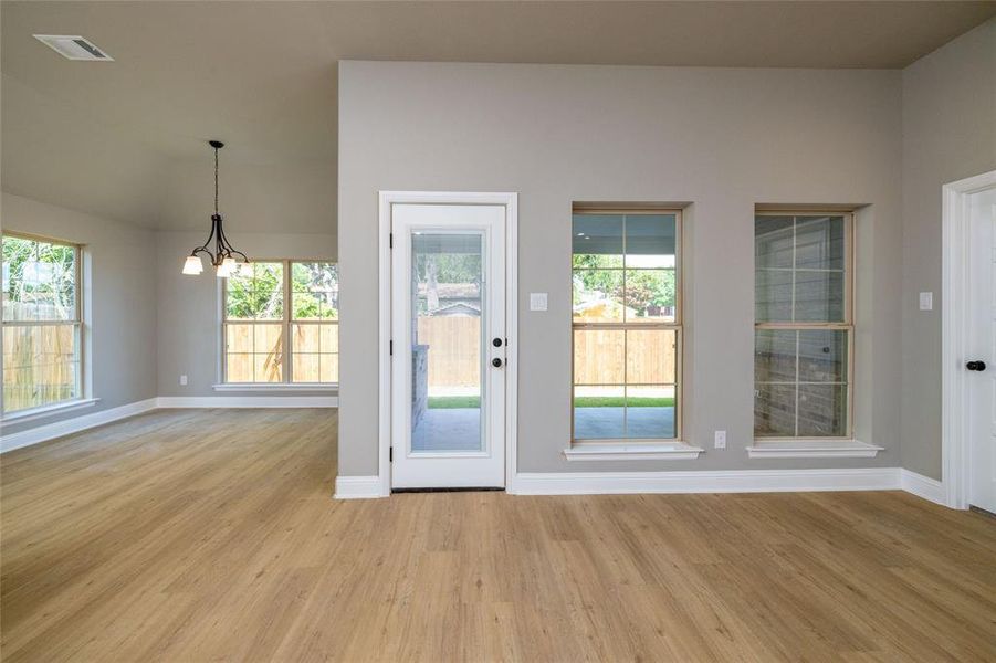 Doorway with light hardwood / wood-style floors and a notable chandelier